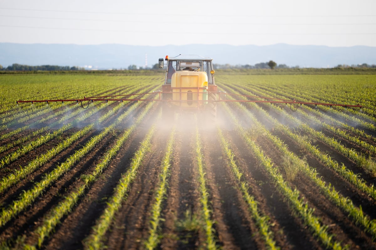 Agricultural spraying equipment working a field at sunset