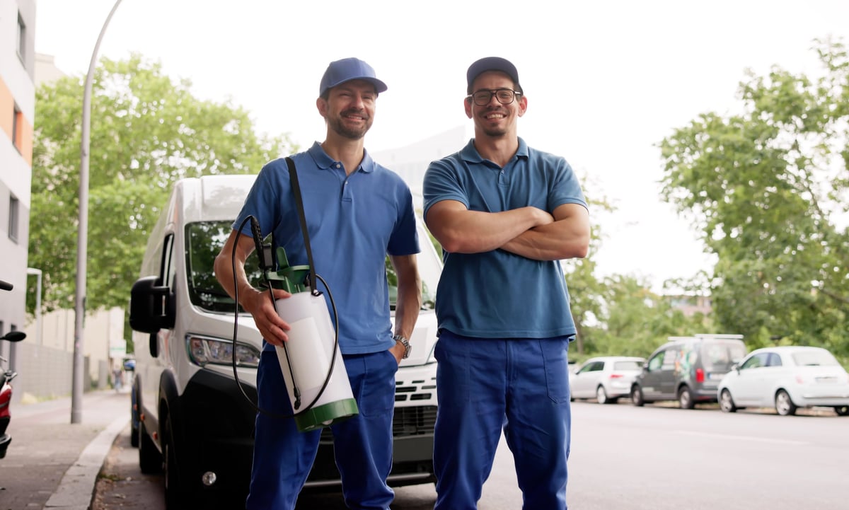 Pest control technician smiling beside a service van